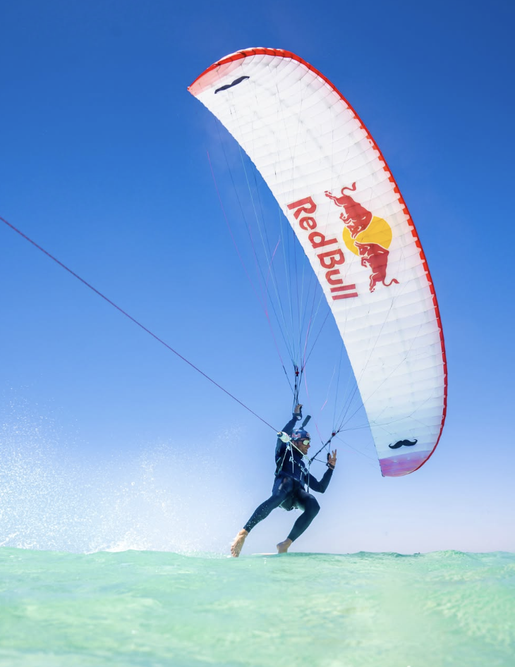 Kitesurfer flying a Red Bull kite over crystal-clear turquoise water
