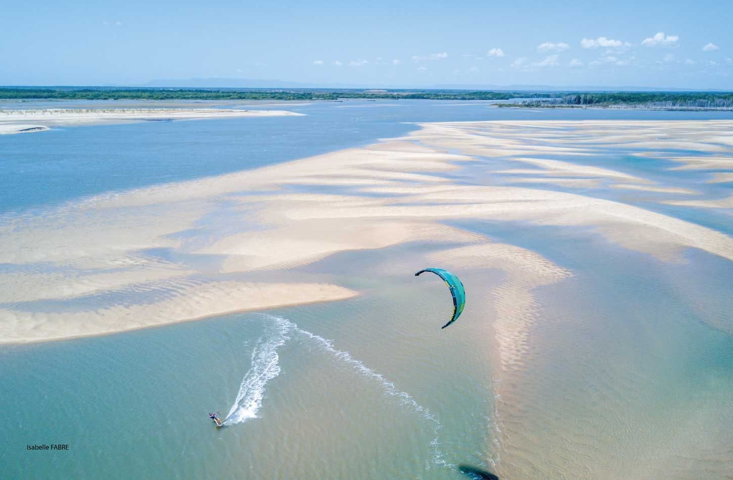 Aerial shot of a kitesurfer crossing sandbanks and shallow turquoise water in Brazil
