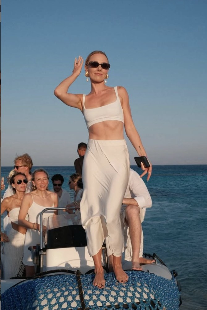 Guest in white standing on the bow of the boat at golden hour