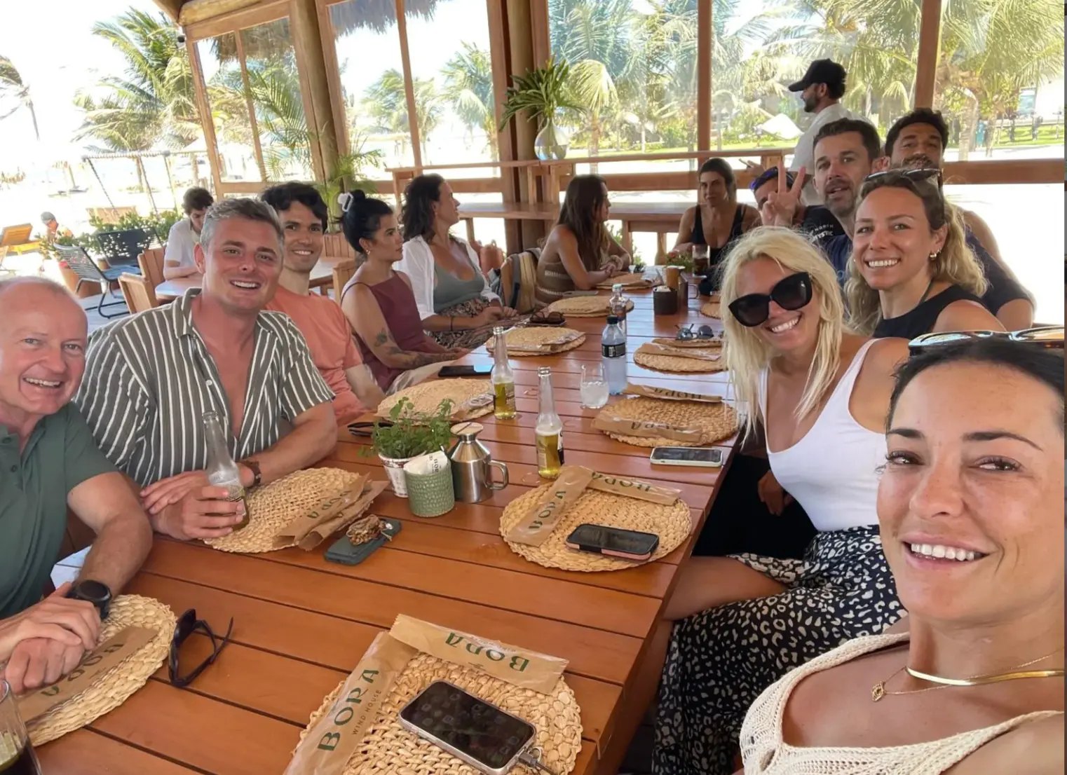 The crew around one long wooden table for lunch at an open-air beach restaurant