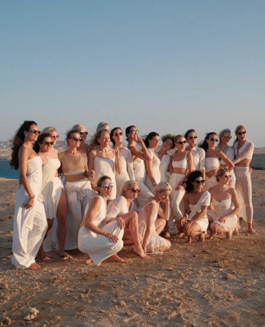 The full crew in white on the rocks above the sea at sunset